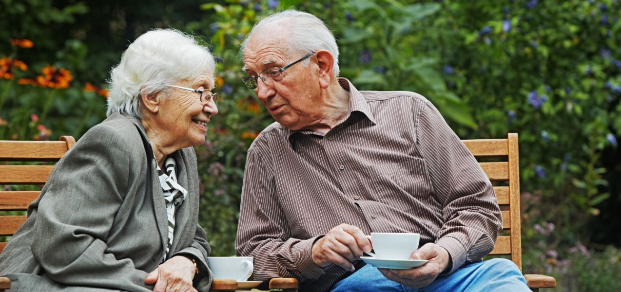 Ein älteres Ehepaar sitz nebeneinander und trinkt Kaffee